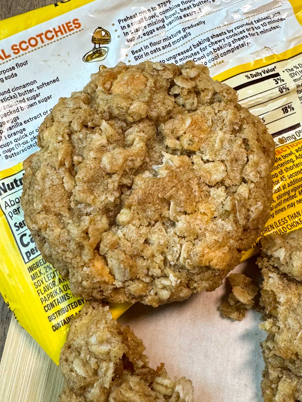 An oatmeal scotchies cookie sitting on the bag of Nestle Toll House butterscotch chips.