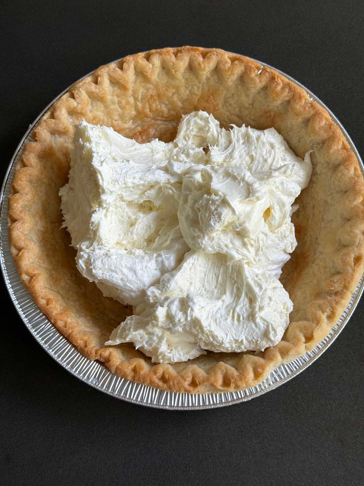 A baked pie shell with fluffy cream cheese filling ready to be spread.