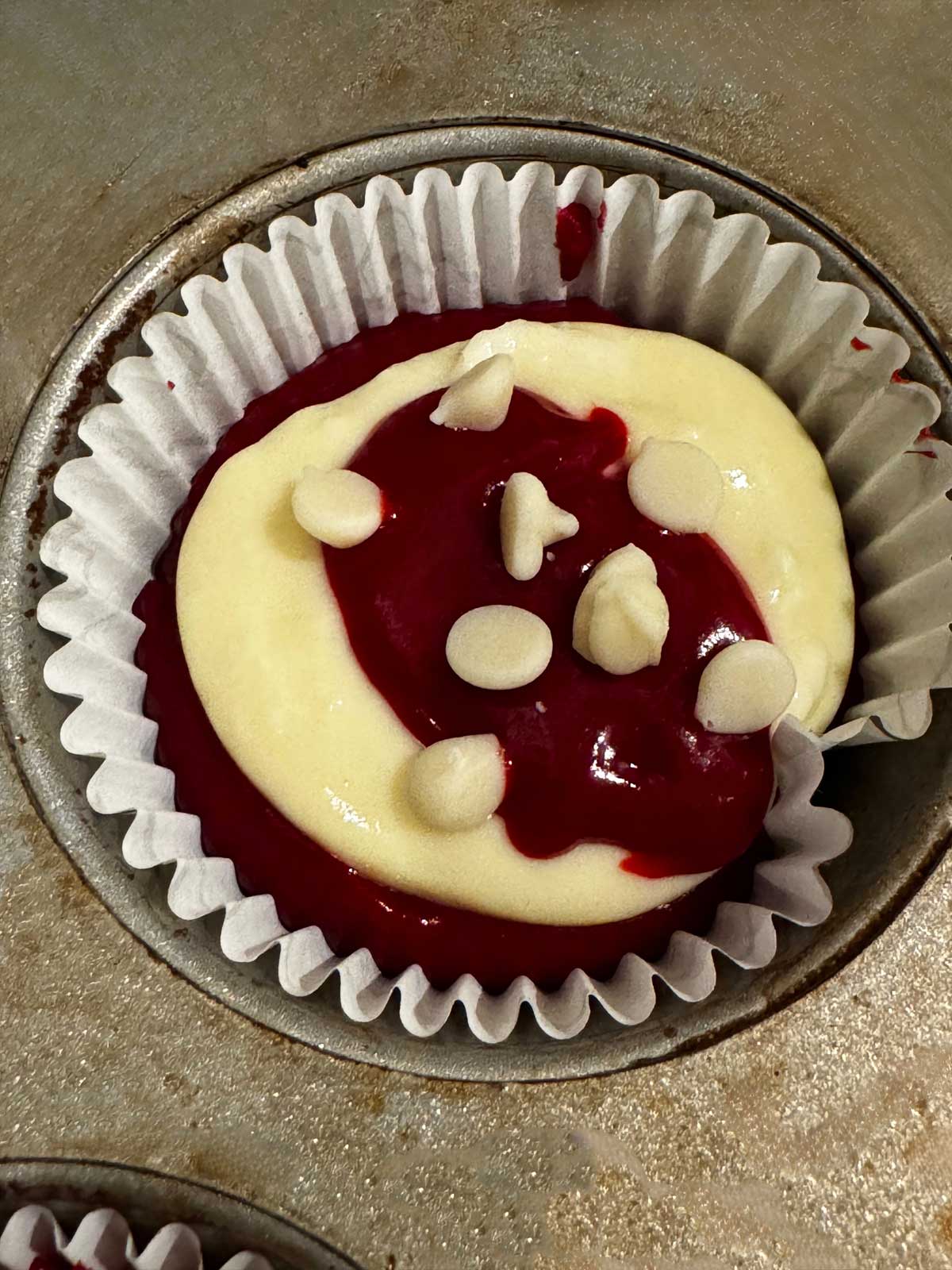 Unbaked Red Velvet Cheesecake Cup showing how much batter to put in the muffin pan.