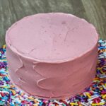 Strawberry layer cake made with enhanced strawberry cake mix and strawberry flavored cream cheese frosting with freeze dried strawberries.
