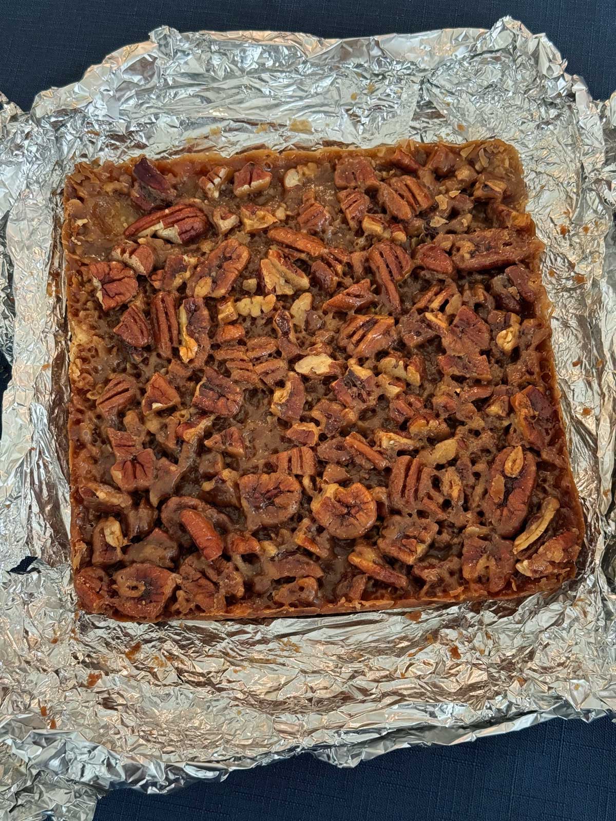Maple Pecan Bars sitting on foil ready to be sliced.