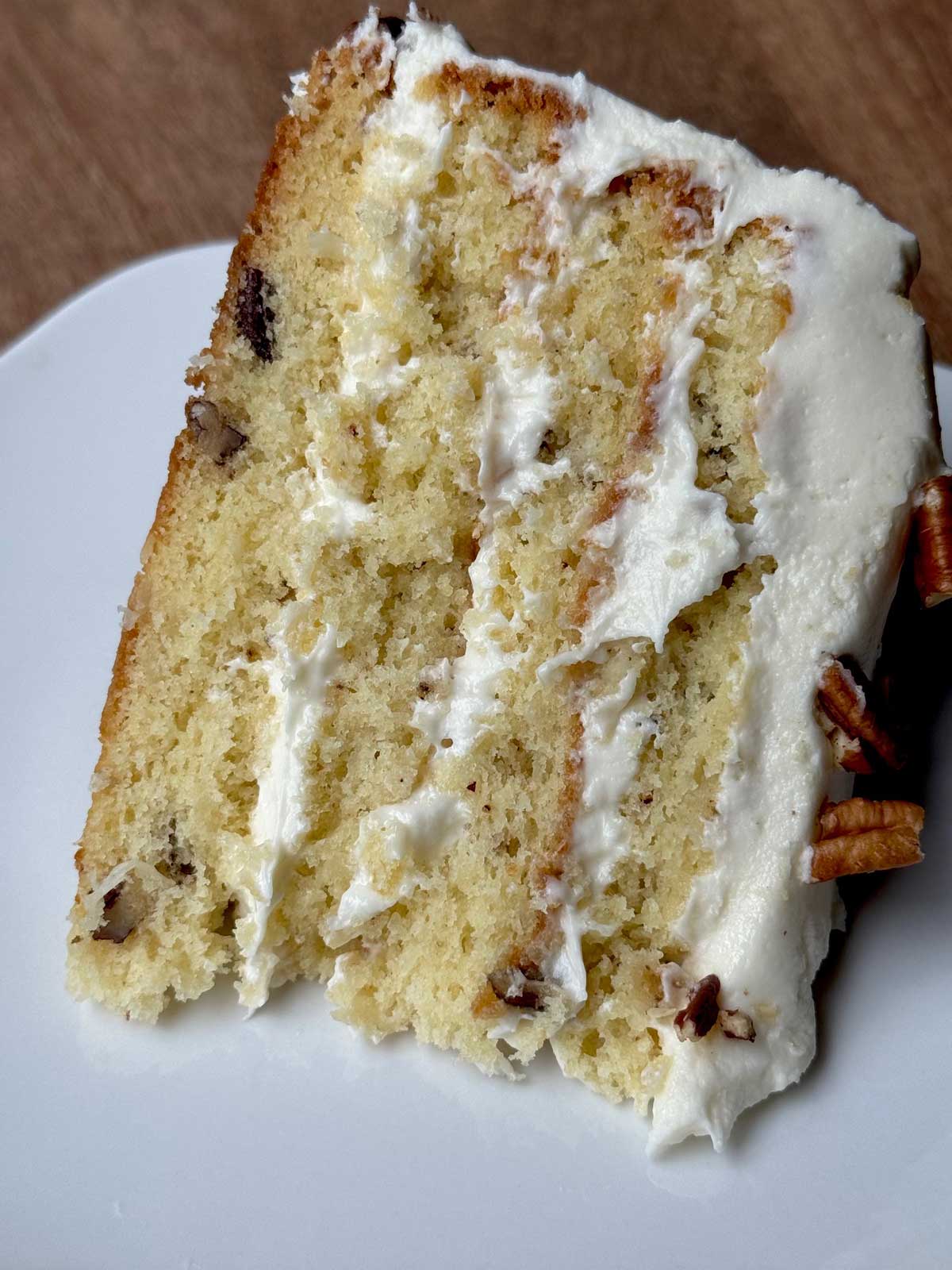 Slice of Italian Cream Cake with four layers and cream cheese frosting.