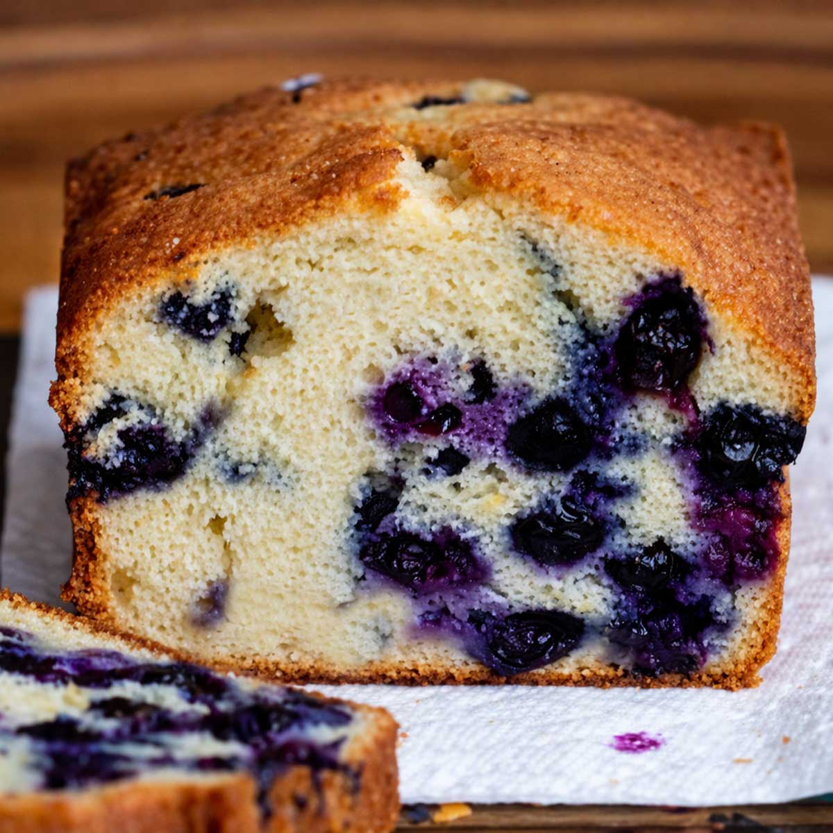 A lemon blueberry loaf cake with frozen fresh berries, sliced to show the crumb.