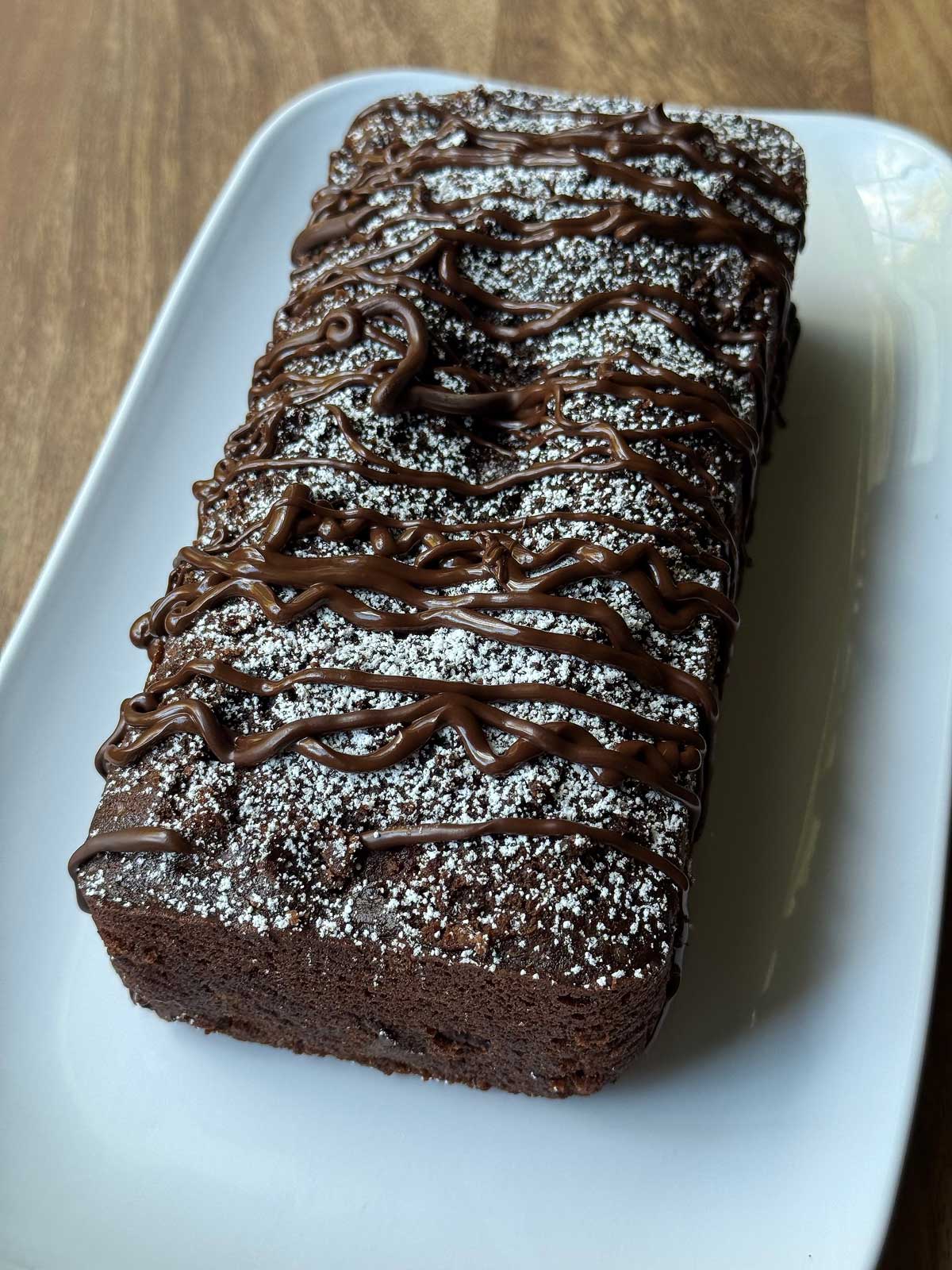 Cherry Chocolate Loaf Cake with a dusting of powdered sugar and drizzle of melted chocolate chips