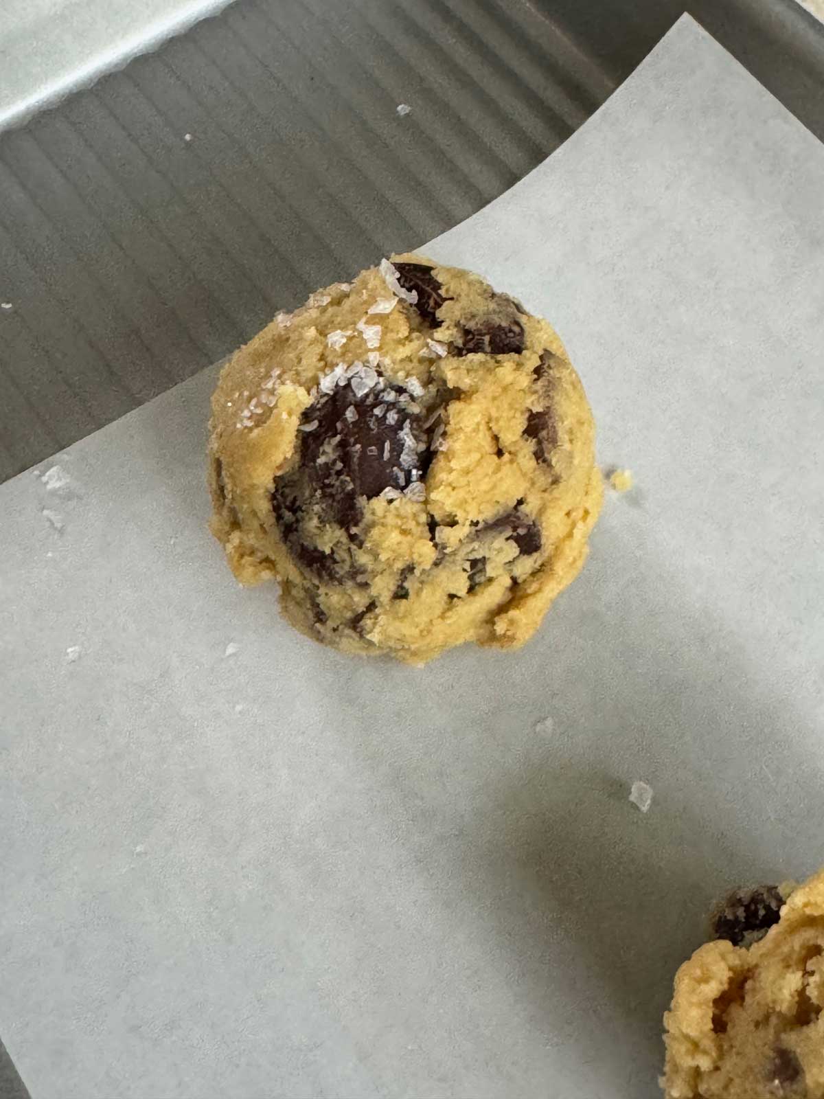 A medium size scoop of chocolate chip cookie dough with sea salt sprinkled on top.