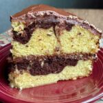 Slice of cake mix enhanced marble cake showing vanilla and chocolate swirl with cocoa frosting