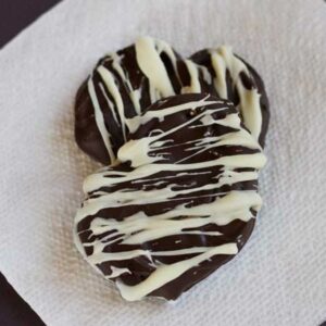 An easy peanut butter pretzel cookie recipe showing chocolate covered pretzels decorated with white chocolate drizzle.