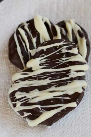 An easy peanut butter pretzel cookie recipe showing chocolate covered pretzels decorated with white chocolate drizzle.