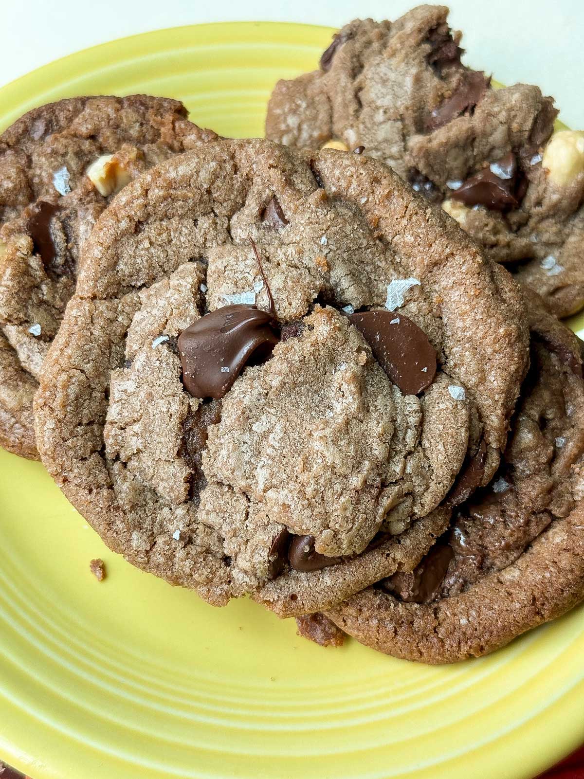 Salted caramel hazelnut chocolate chip cookies on a yellow plate.