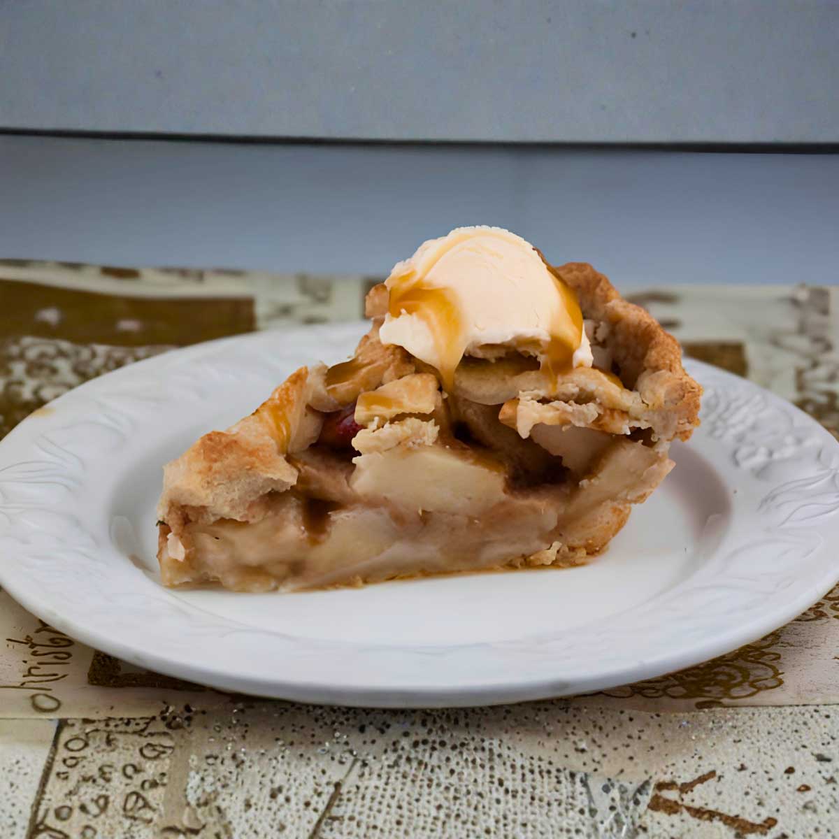 A slice of basic apple pie topped with a scoop of HEB brand 1905 vanilla ice cream and a little caramel sauce. 
