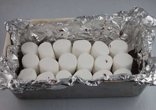 chocolate marshmallow squares being assembled in a loaf pan.