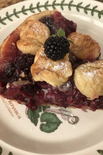 A slice of blackberry pie with buttery pastry crust.