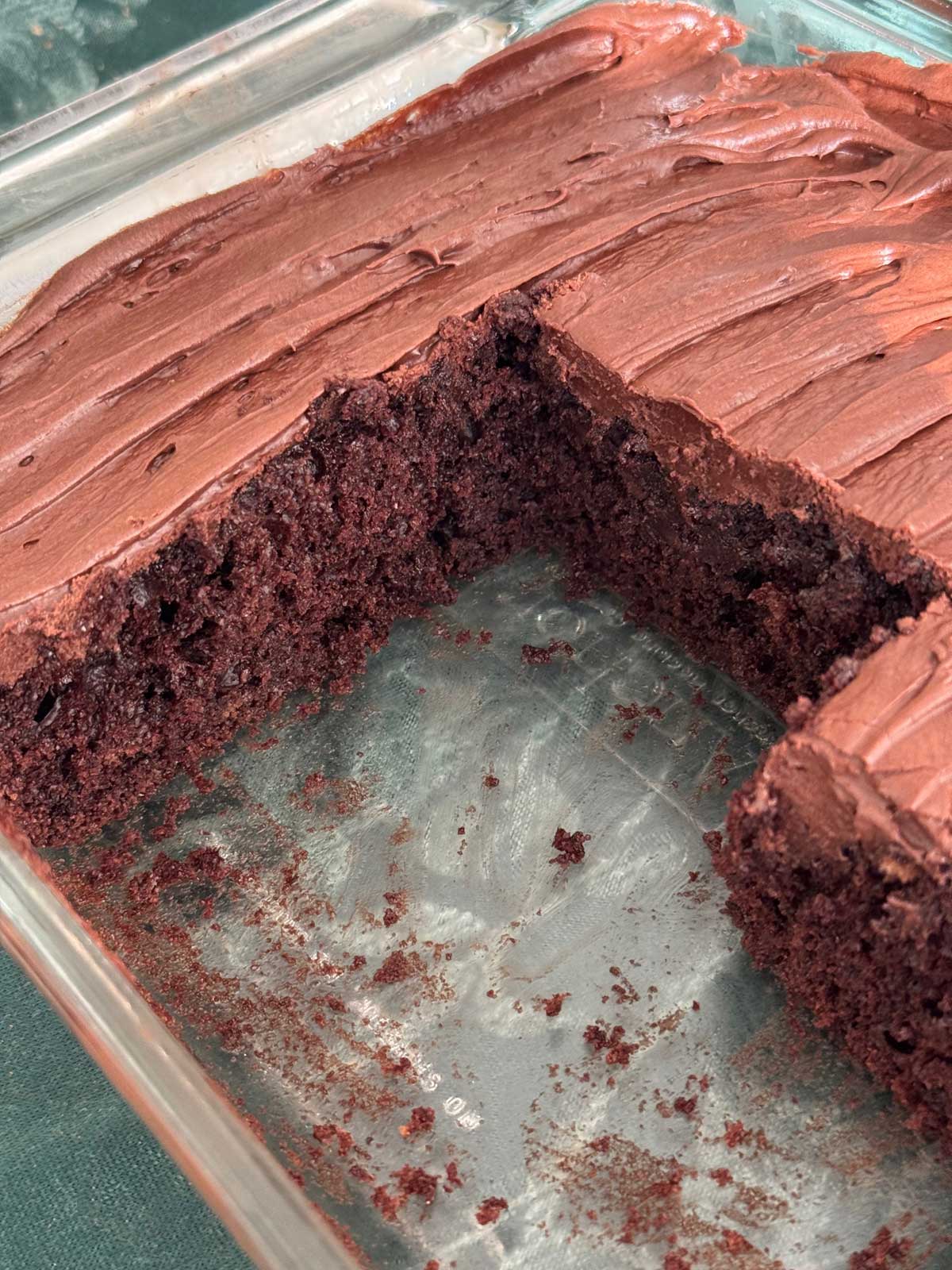 An 8-inch square glass pan with chocolate cake and sour cream chocolate frosting.