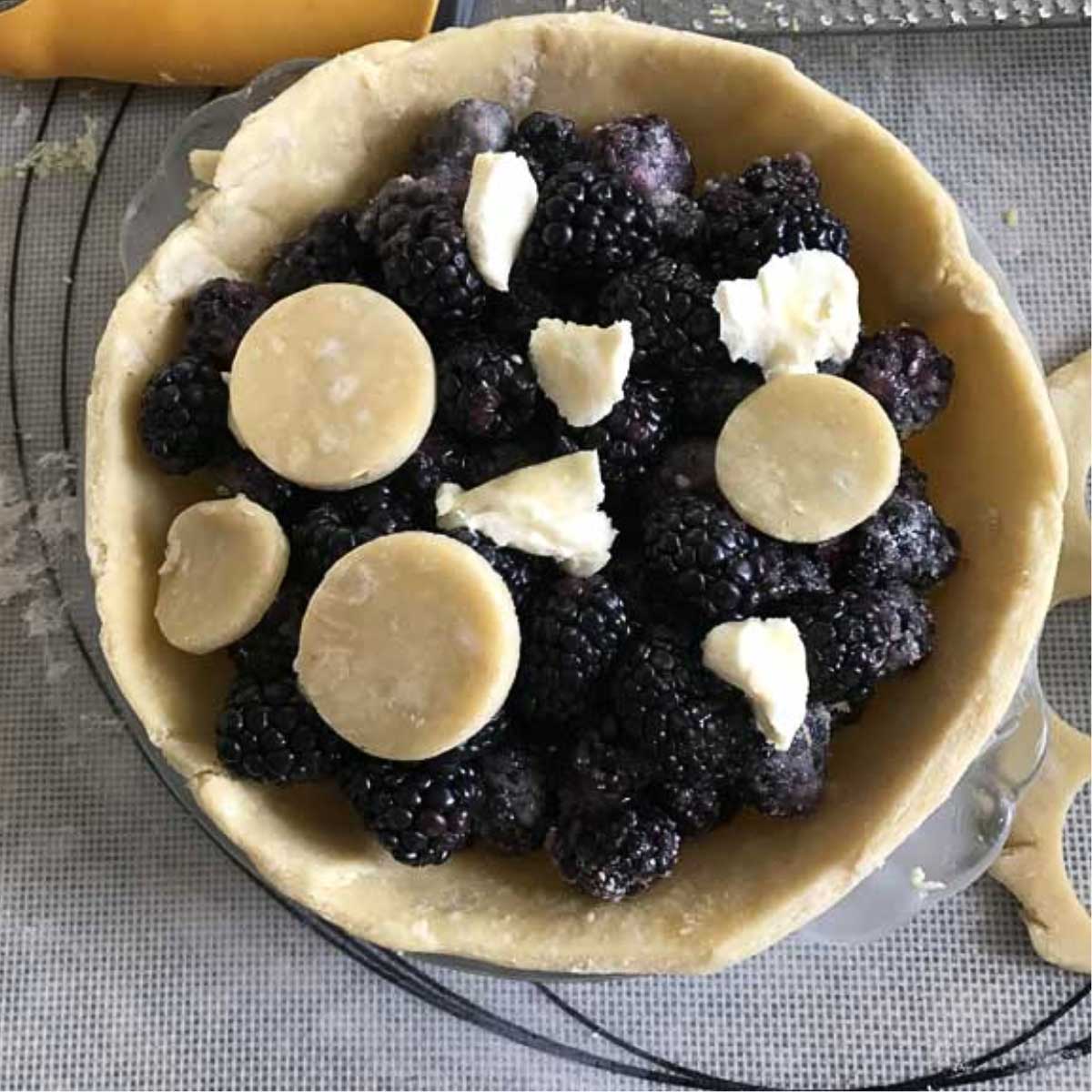 Unbaked blackberry pie showing crust, filling and bits of unbaked pastry crust on top.