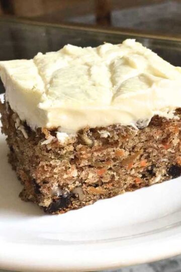 White chocolate cream cheese frosting on a slice of carrot cake baked in a sheet pan for a potluck.