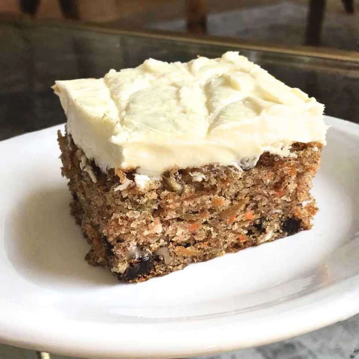 White chocolate cream cheese frosting on a slice of carrot cake baked in a sheet pan for a potluck.