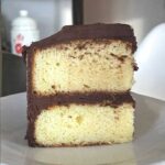 A slice of Six Inch Yellow with Chocolate Frosting with two layers.
