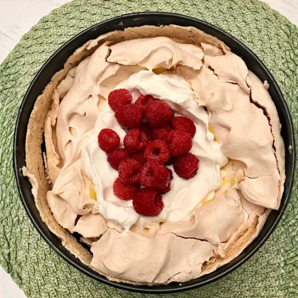 Pavlova filled with lemon curd, whipped cream and fresh berries using a very easy recipe.