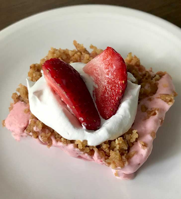 Frosty Strawberry Squares dessert sitting on a white plate. Frosty Strawberry Squares