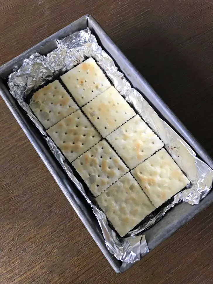 Saltine crackers on top of unbaked brownie batter in a loaf pan.