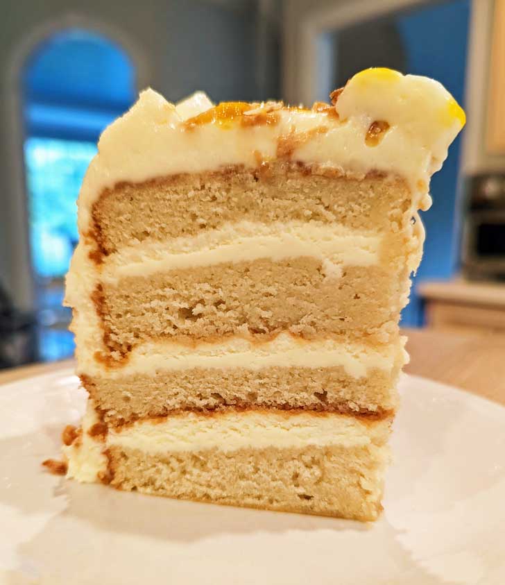 6-inch flour layer coconut cake sitting on a white plate with the kitchen in the background.