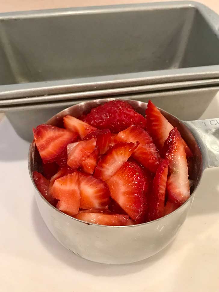 Cup of strawberries ready to put in strawberry quick bread.