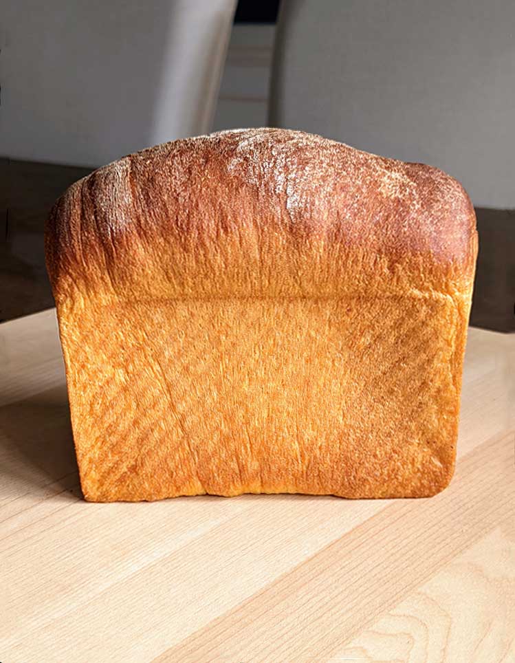 Tall loaf of Sweet Potato Yeast Bread baked in a Pullman loaf pan.