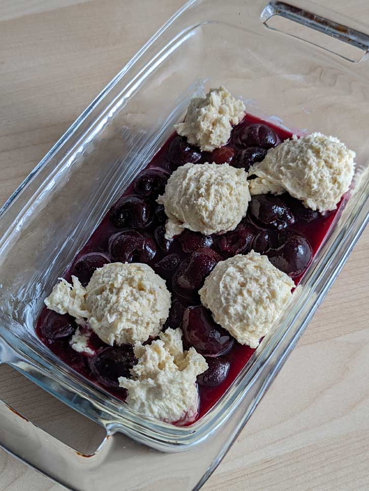 Unbaked cherry cobbler in a glass loaf pan.