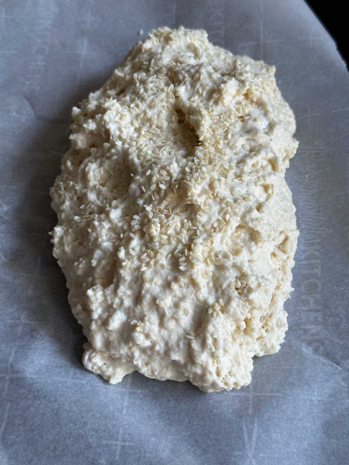 An unbaked loaf of no-yeast bread on a piece of parchment paper.