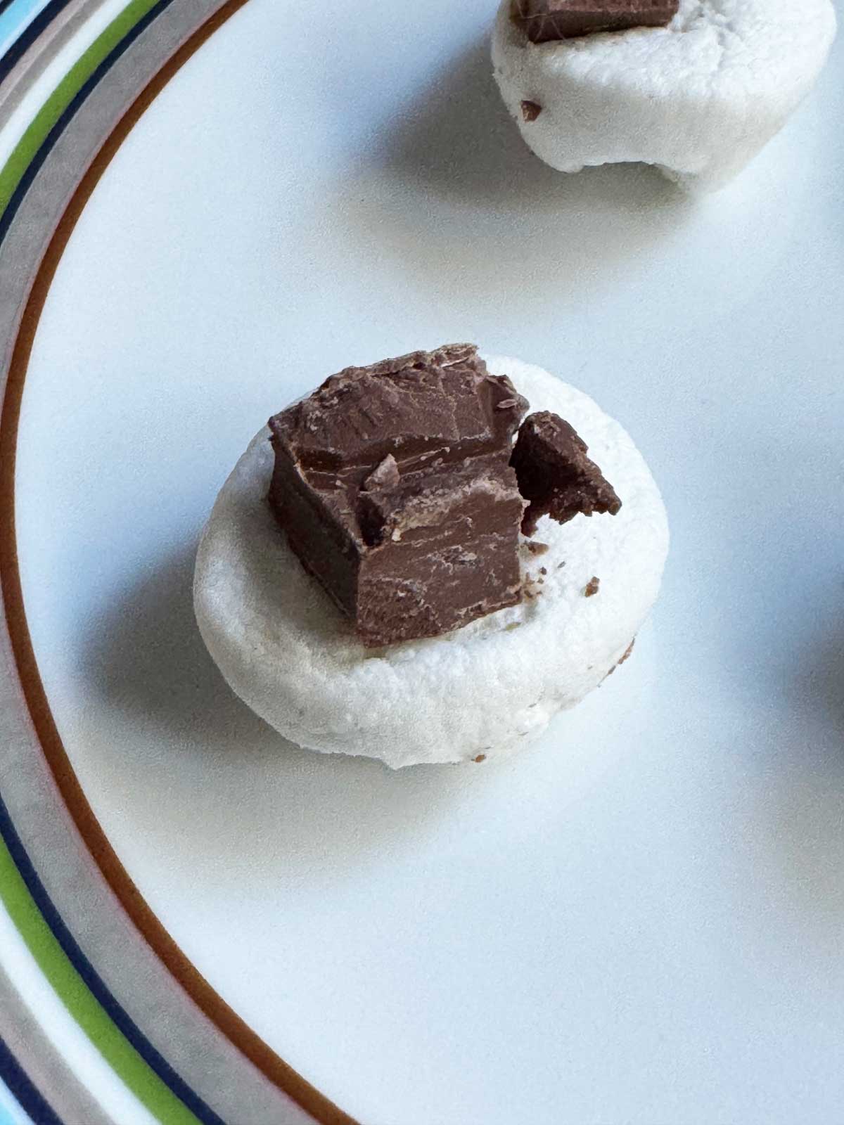 A large marshmallow with a chunk of milk chocolate on top that will go on the partially baked cookies.