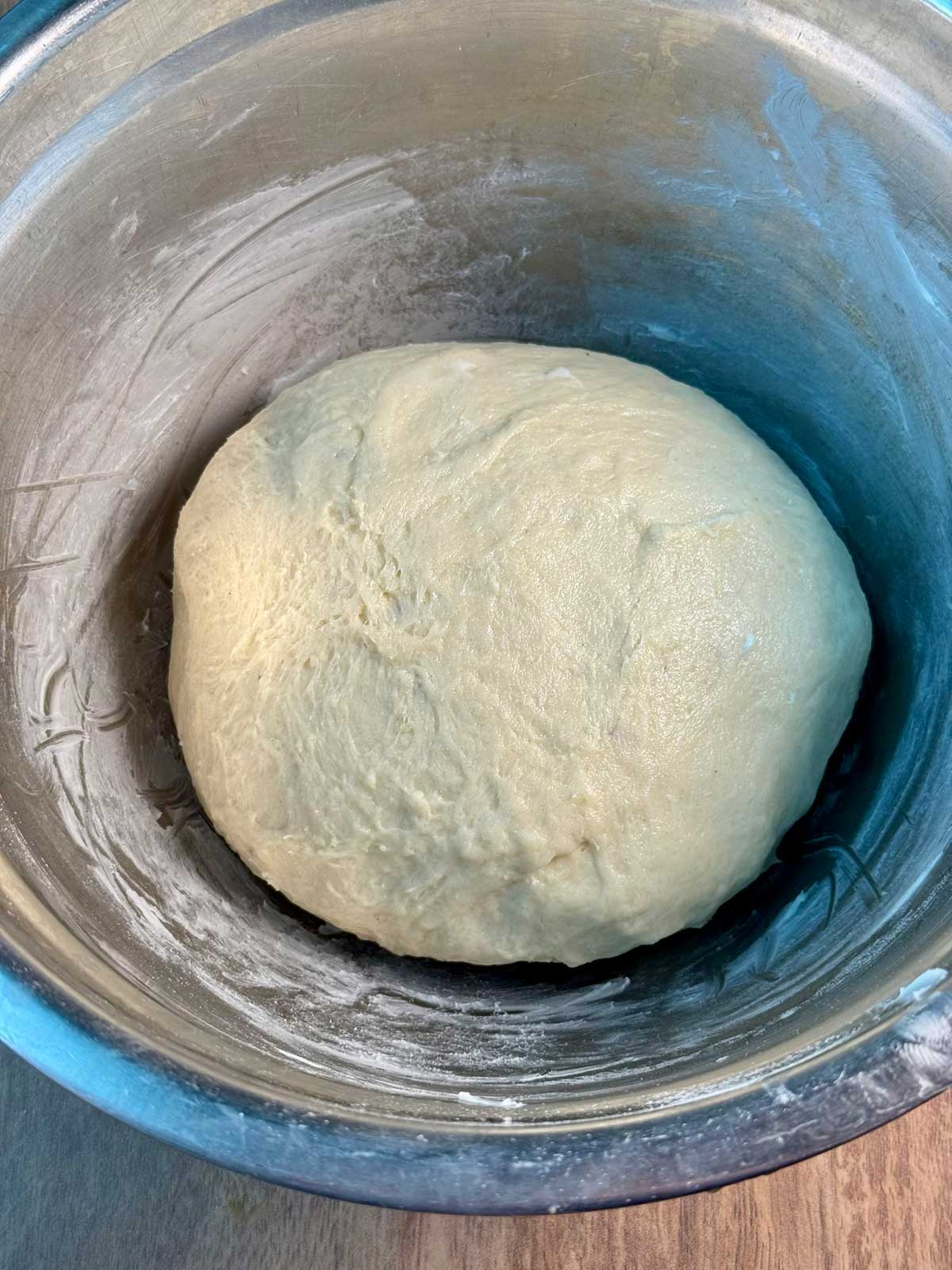 Mashed potato bread dough in a greased bowl ready to rise.