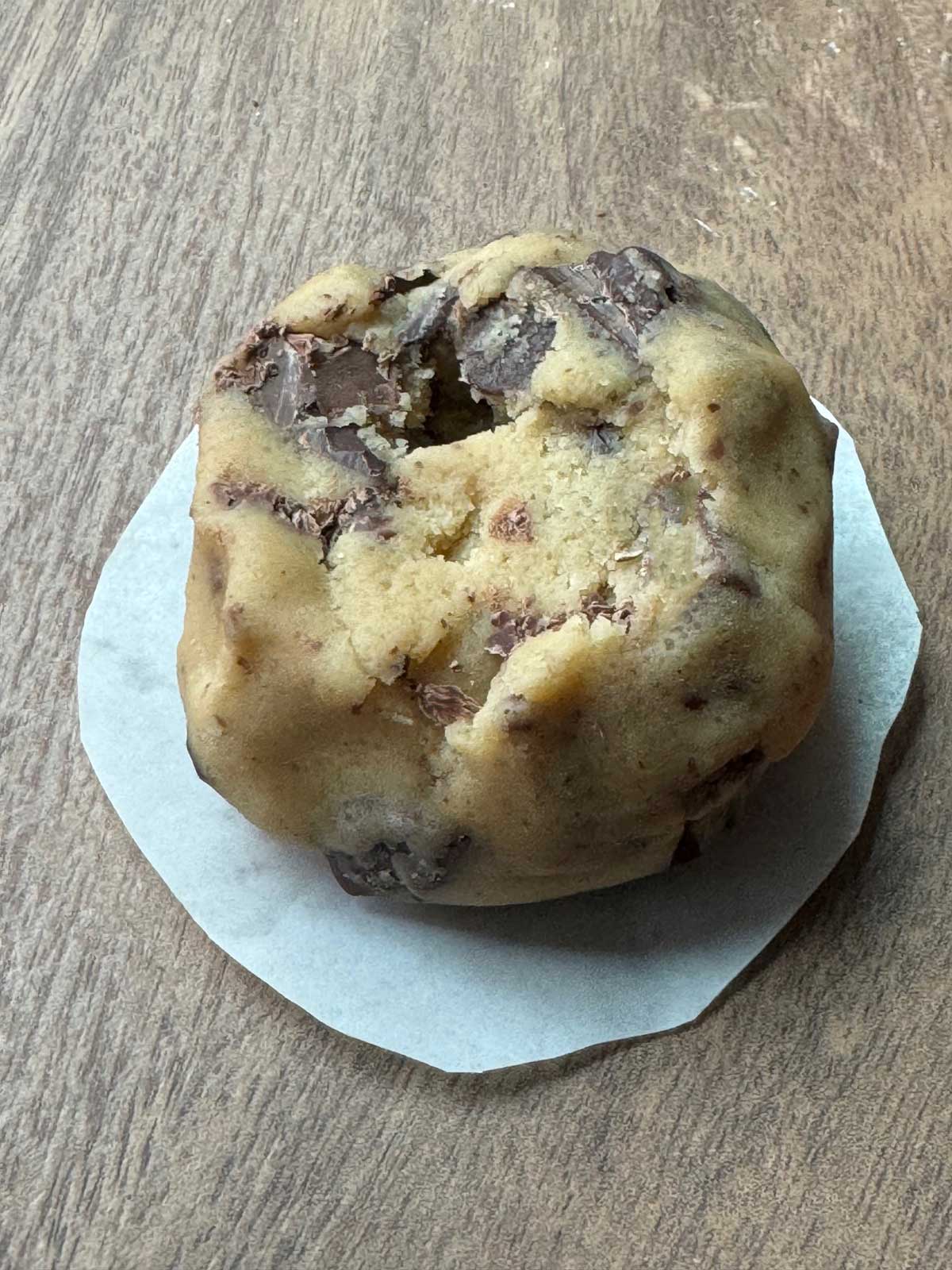 Chocolate chip cookie dough sitting on a round of parchment paper for air fryer.