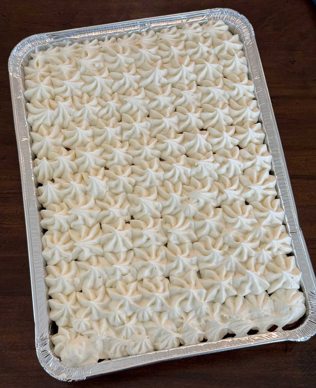 Classic carrot cake with whipped cream cheese frosting baked in a disposable 9x13 inch pan.
