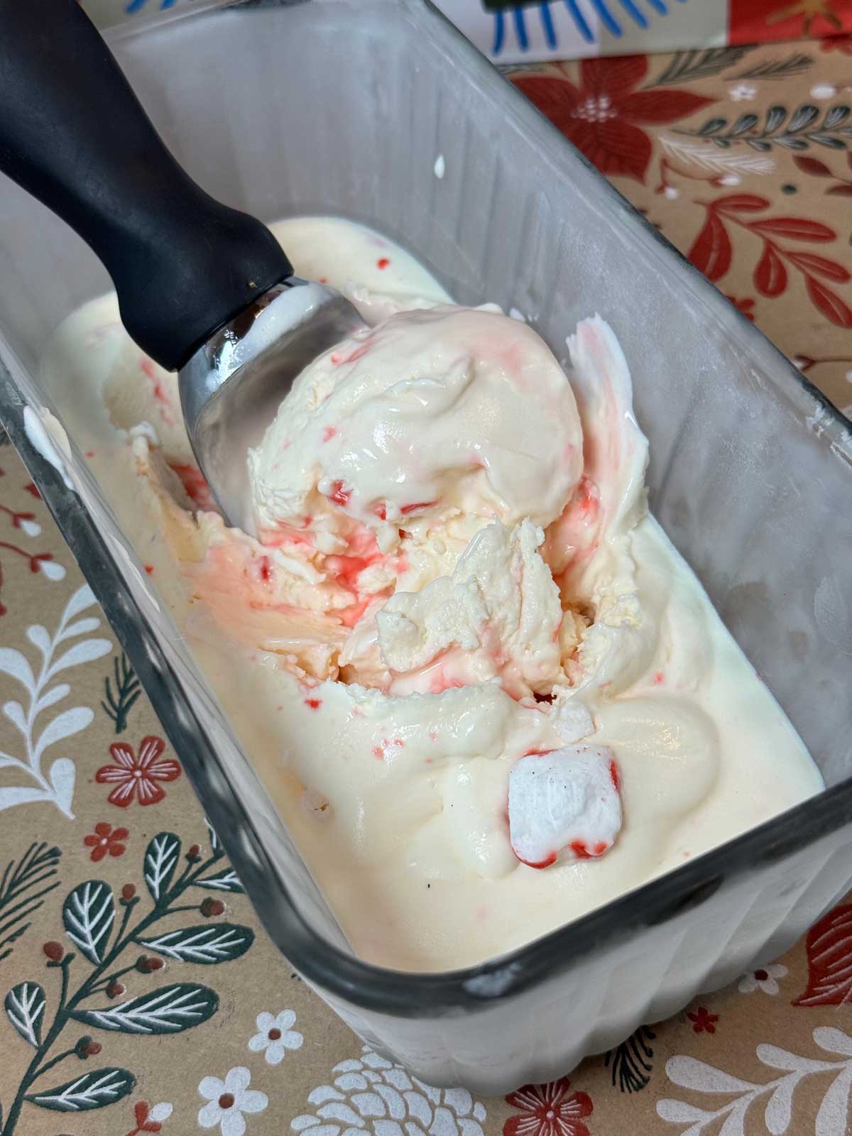 Eagle Brand No Churn Peppermint Ice Cream being scooped out of a glass loaf pan.
