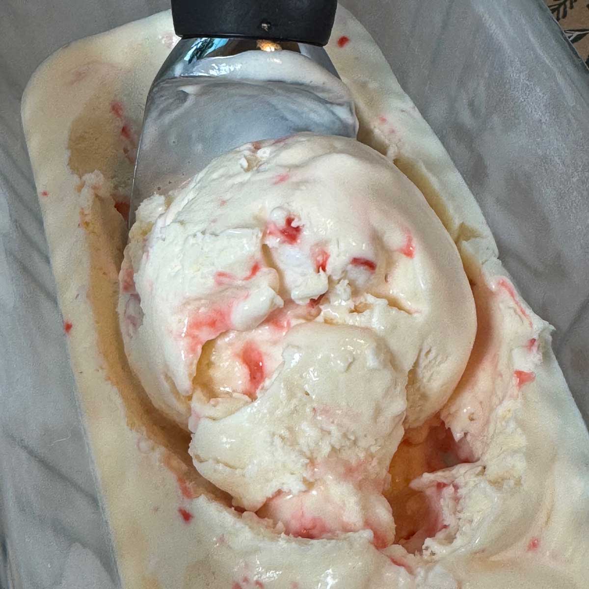 Eagle Brand No Churn Peppermint Ice Cream being scooped out of a glass loaf pan.