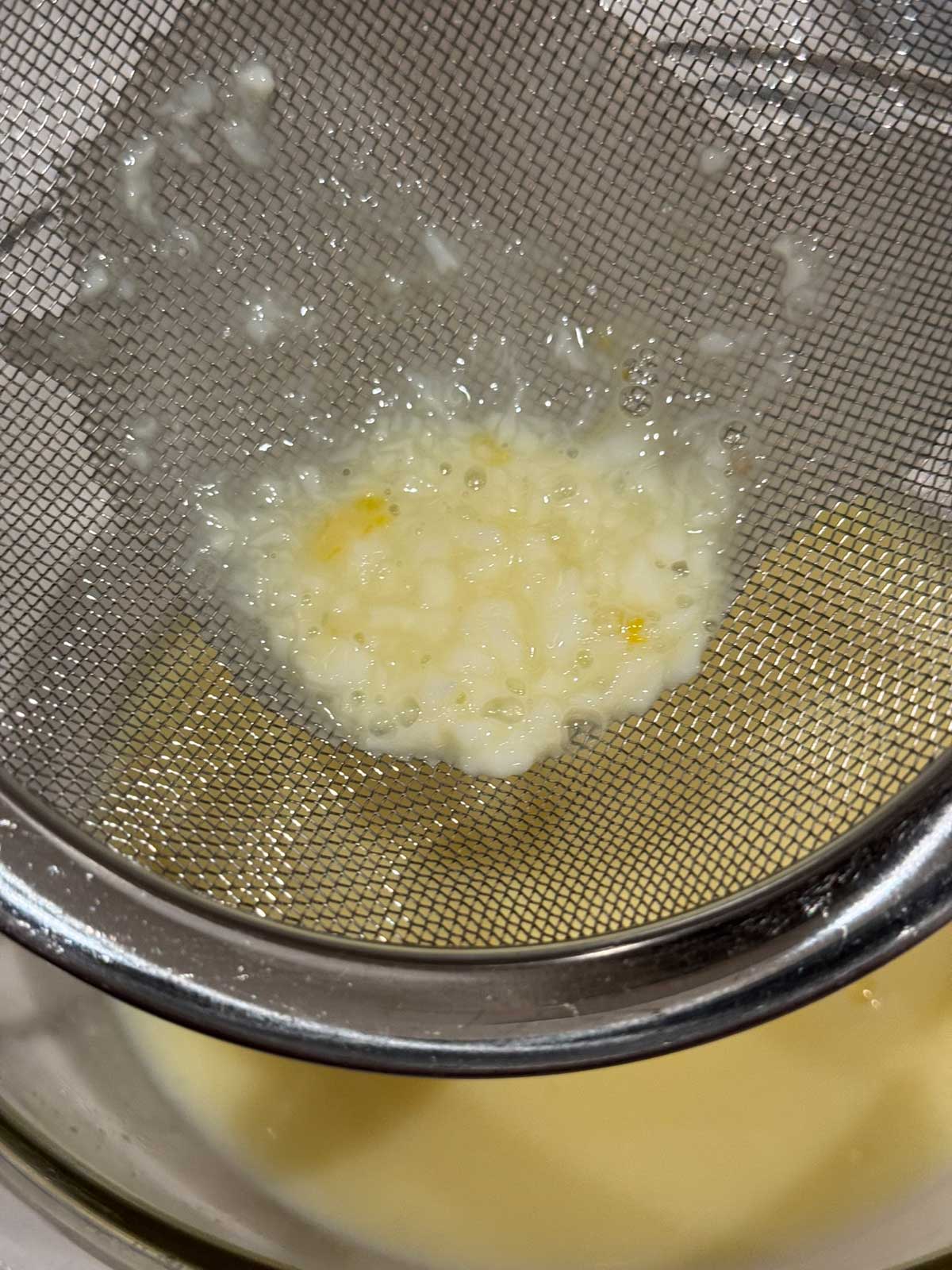 Straining cooked egg bits from allulose ice cream custard.