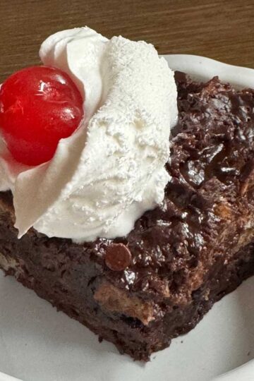 Chocolate Bread Pudding made with cubes of sourdough and topped with whipped cream and a cherry.