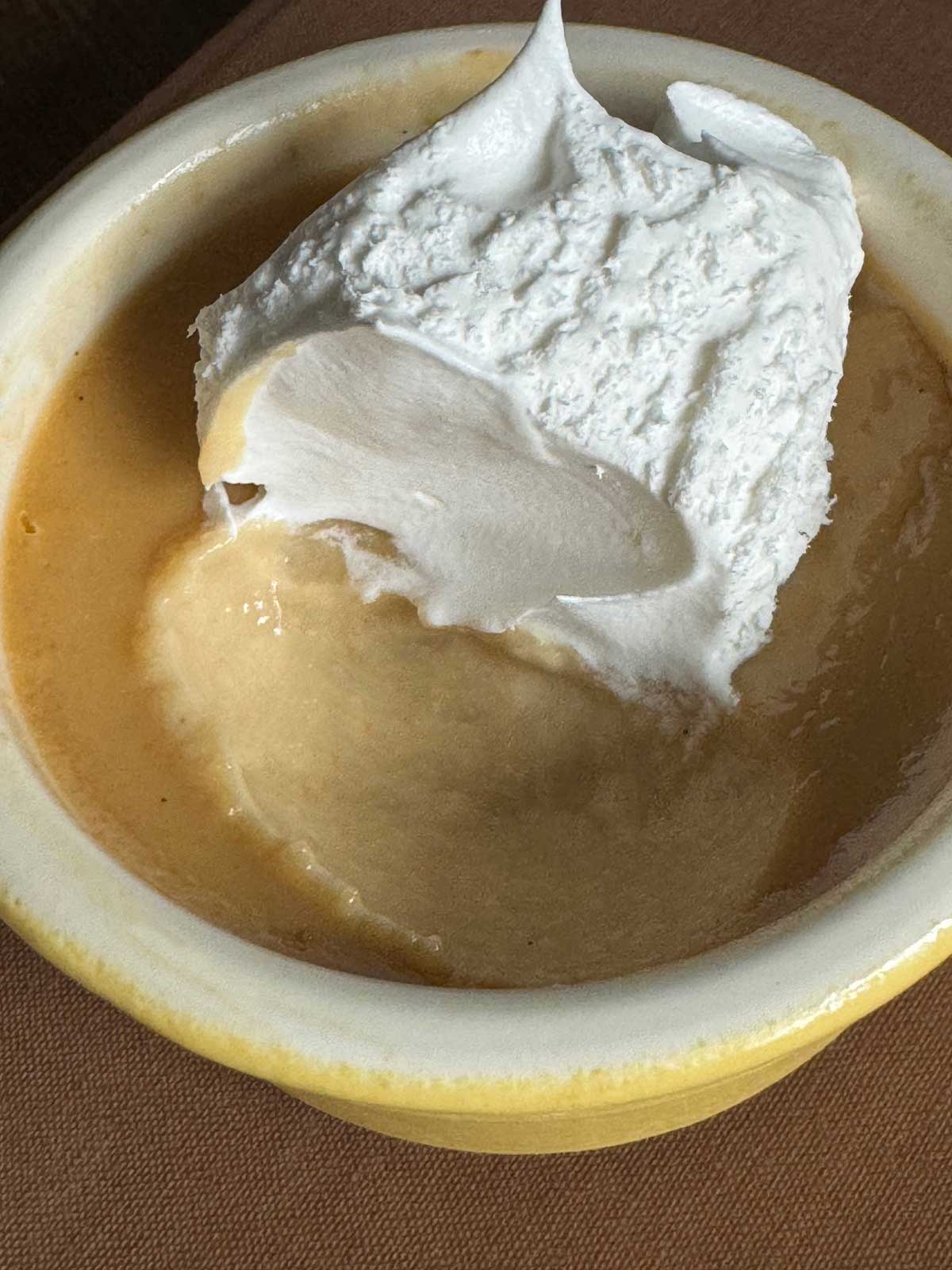 Individual maple custard with a spoonful taken out to show texture.