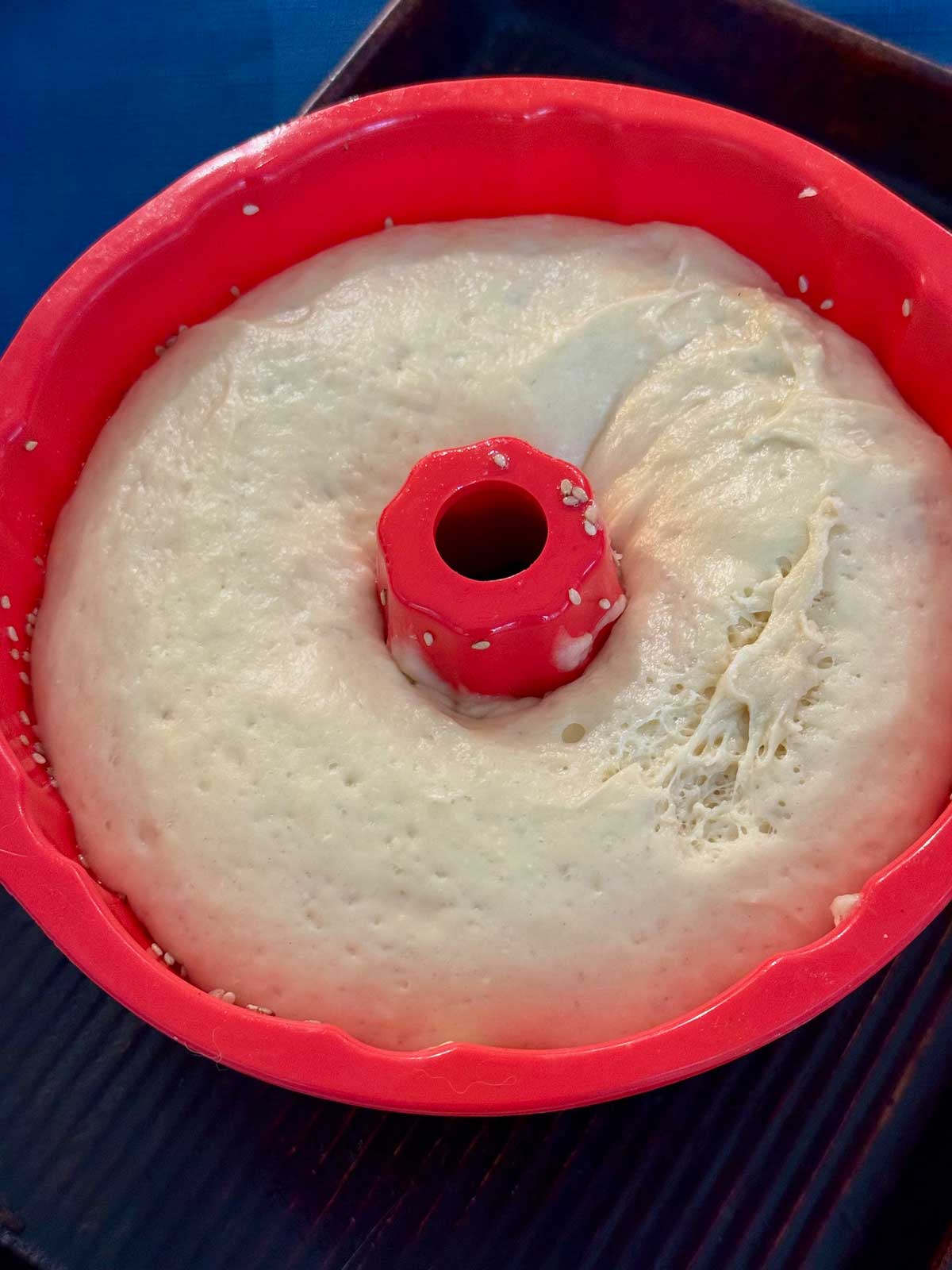 Risen buttery batter bread dough in a 6-cup silicone Bundt pan ready to be baked.
