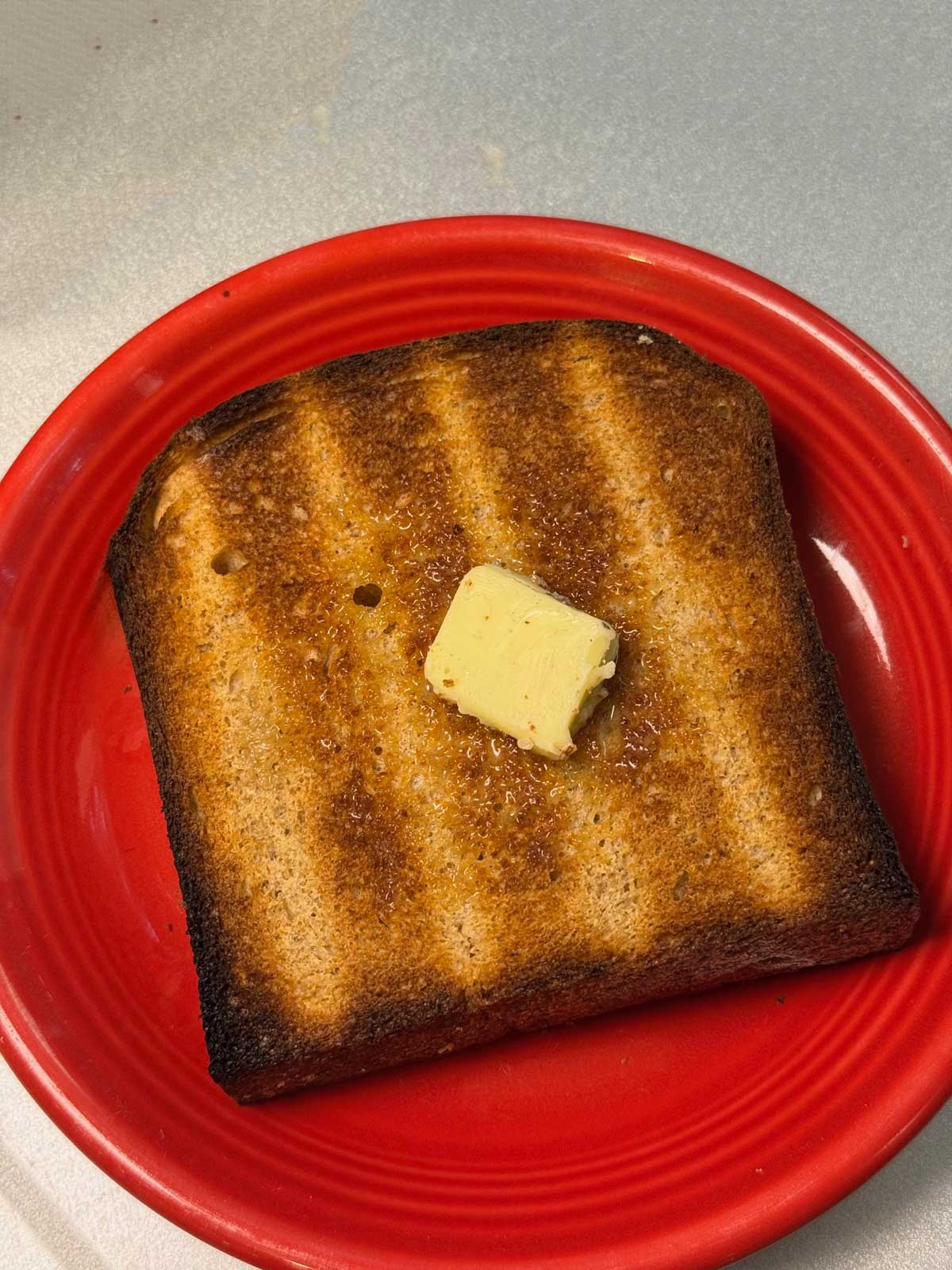 Whole Grain Wheat Bread from the KitchenAid mixer manual, toasted with butter on it.