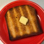 Whole Grain Wheat Bread from the KitchenAid mixer manual, toasted with butter on it.