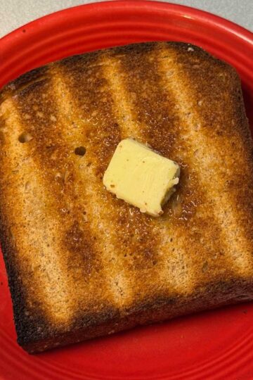 Whole Grain Wheat Bread from the KitchenAid mixer manual, toasted with butter on it.