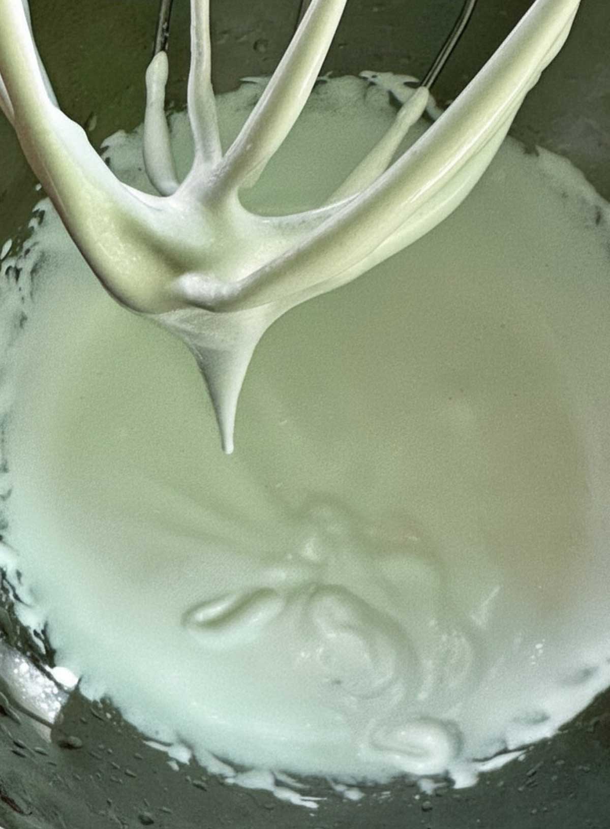 Whipped aquafaba and sugar in a stand mixer bowl.