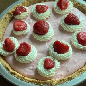 Strawberry Cream Pie garnished with whipped cream and frozen thawed strawberries.