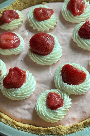 Strawberry Cream Pie garnished with whipped cream and frozen thawed strawberries.