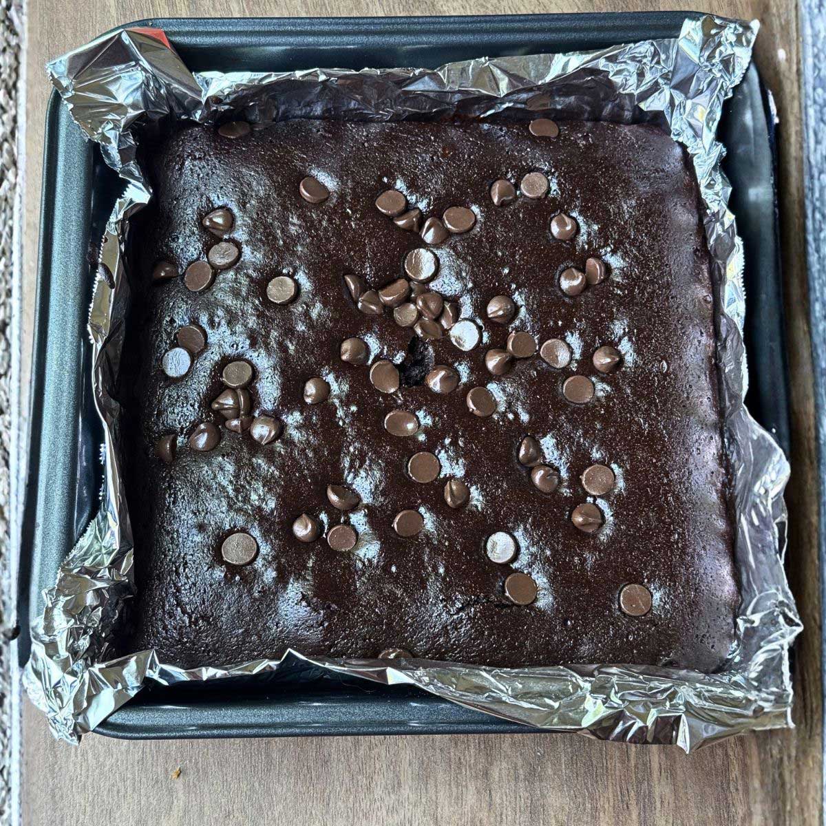 Allulose sweetened gluten-free brownies baked in an 8-inch square metal pan lined with foil.