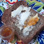 Dark buckwheat bread toasted and smeared with butter and orange marmalade.