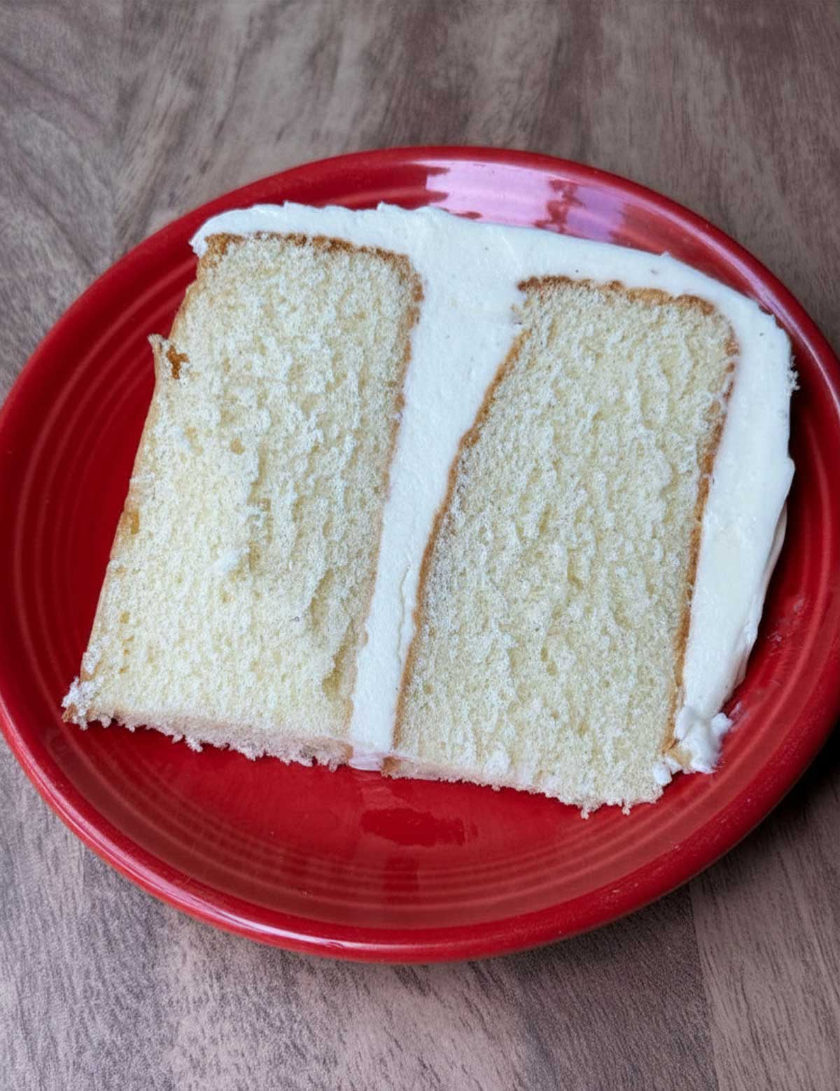 A thick slice of yellow vanilla cake with easy vanilla buttercream frosting without confectioners' sugar.