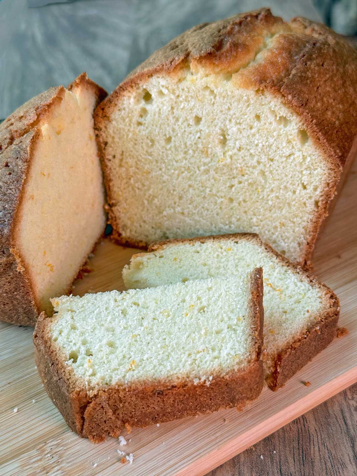 Recipe for soft orange loaf cake with photo showing texture of slices and brown crust.