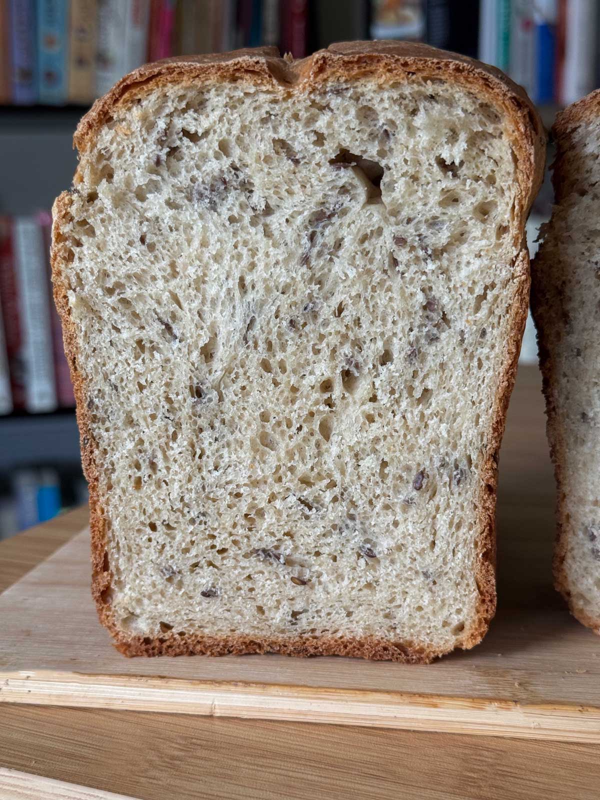 A tall loaf of buckwheat bread sliced to show texture and flaxseeds.